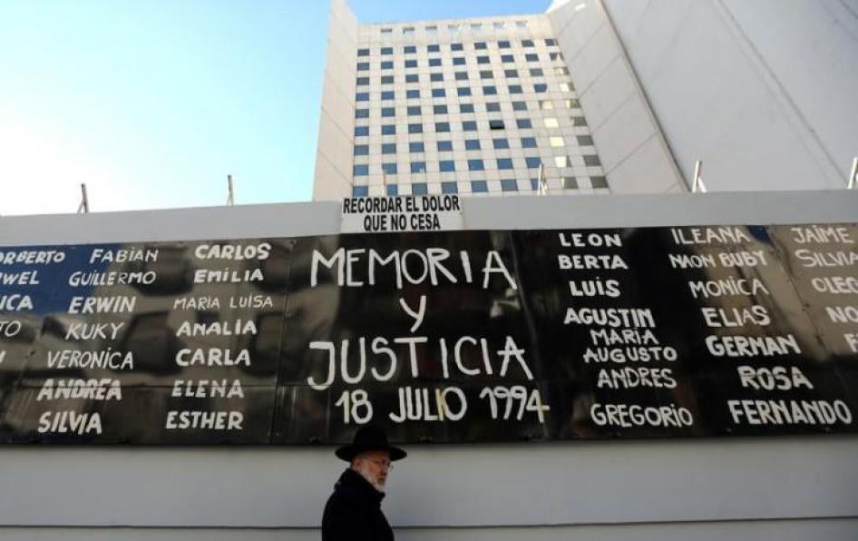 A man walks by a sign that reads "Memory and Justice" next to the names of the victims of the 1994 Argentine Israeli Mutual Association (AMIA) bombing