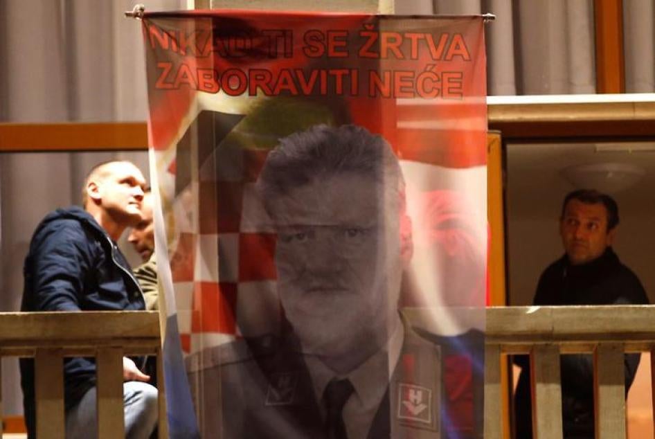 Bosnian Croats in Mostar, Bosnia and Herzegovina hang a flag displaying a portrait of General Slobodan Praljak and a message that reads "Your sacrifice will never be forgotten", as people pray and light candles for the convicted general.