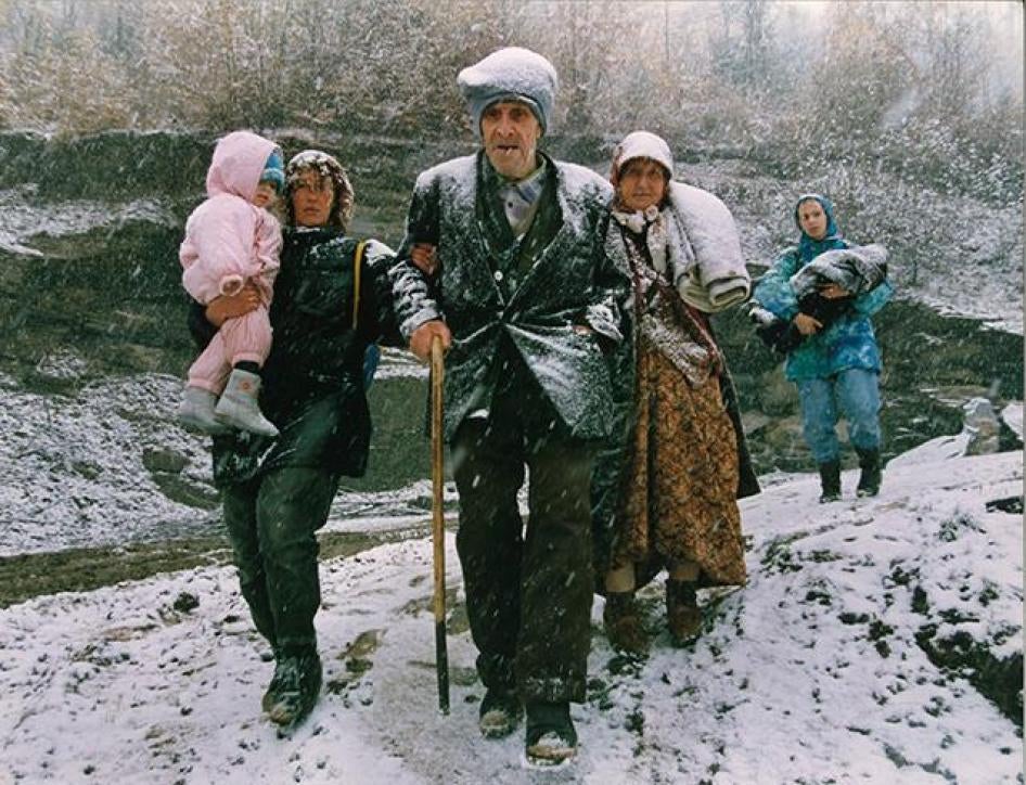 A family flee on foot through heavy snowfall after fleeing fighting in their town, November 14, 1993.