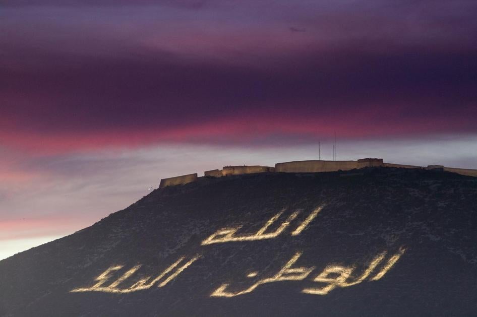 شعار المغرب "الله، الوطن، الملك" يضيء على تلّة في أغادير. هذا الشعار هو أساس الخطوط الحمراء التي تقيّد التعبير في المملكة. © 2017 غيتي إيمجز