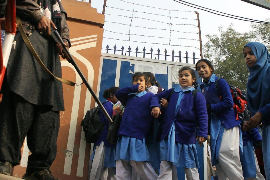 Des écolières pakistanaises devant le portail de leur école à Lahore, en présence d’un garde armé le 1er janvier 2015, deux semaines après l'attaque perpétrée le 16 décembre 2014 par des Talibans pakistanais contre une école publique gérée par l’armée à P
