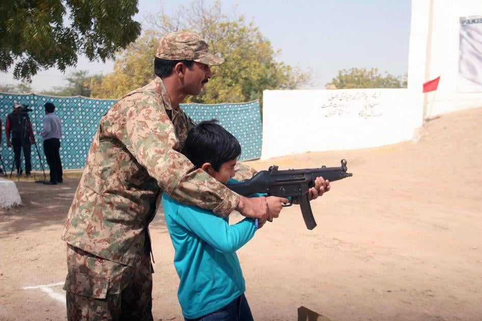A Pakistani soldier assists a child aim a military assault rifle during a security training in Karachi, Pakistan, February  2016.