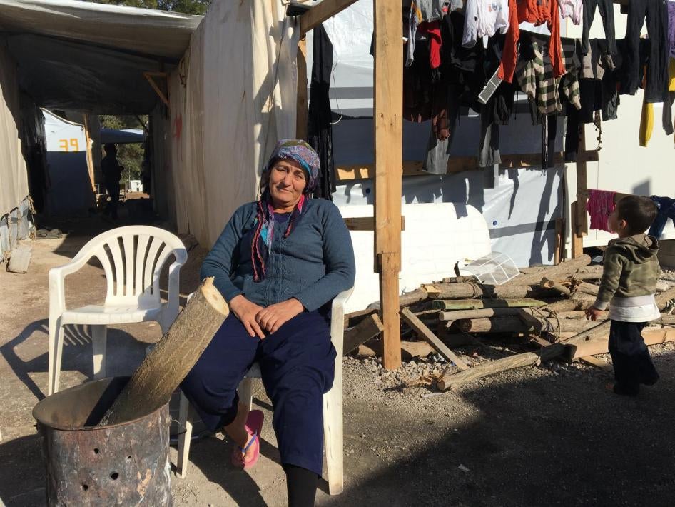 An older woman sits outside caravans in a camp for asylum seekers, near Athens, Greece. © 2016 Human Rights Watch