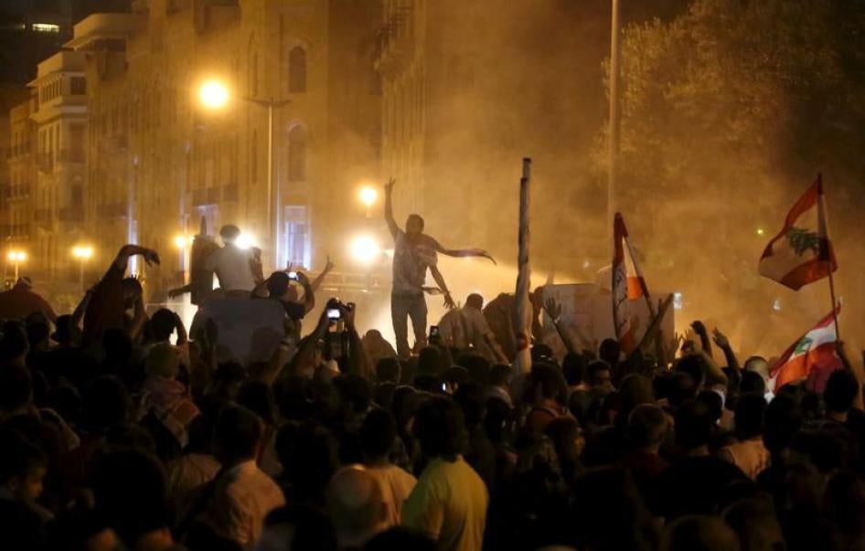 متظاهرون يرفعون علامة النصر بينما قوات الأمن تطلق مدافع المياه في ساحة الشهداء، وسط بيروت، أكتوبر 8، 2015