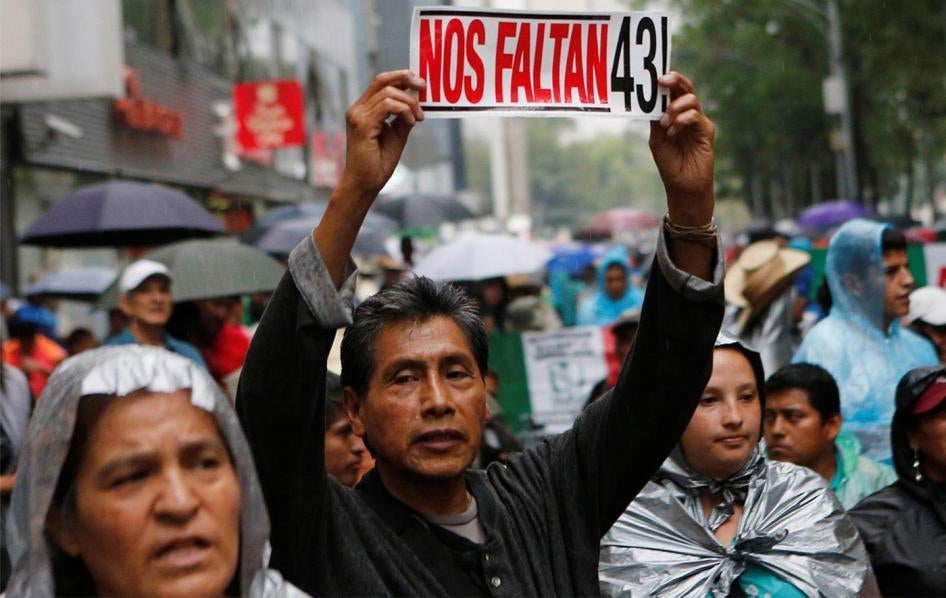 A protester holds up a sign – "We are missing 43!" – with relatives of the 43 missing students from a teacher’s college in Ayotzinapa during a march in Mexico City. © 2016  Henry Romero/Reuters
