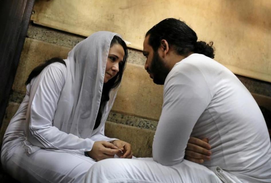 Aya Hegazy and her husband Mohamed Hassanein, founders of a nongovernmental organization that looks after street children, sit on the ground talking inside a holding cell as they face trial on charges of human trafficking, sexual exploitation of minors, a