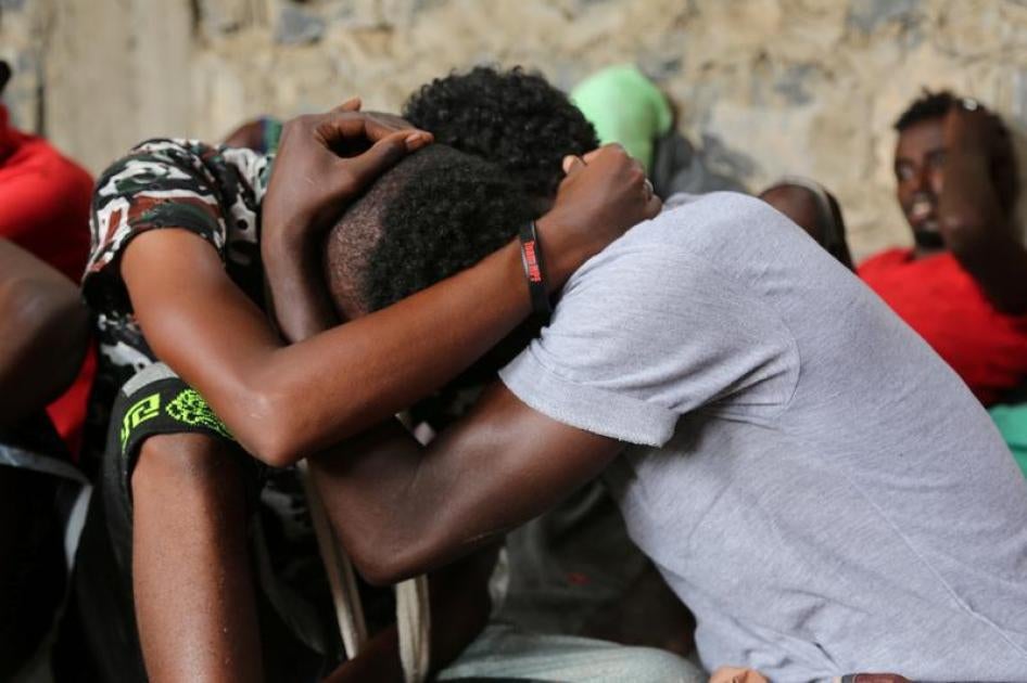 لاجئون صوماليون ناجون من هجوم استهدف مركبهم قبالة الساحل اليمني على البحر الأحمر، يعانقون بعضهم البعض وهم جالسون في مركز احتجاز في مدينة الحديدية الساحلية الخاضعة لسيطرة الحوثي، اليمن، 22 مارس/آذار 2017.