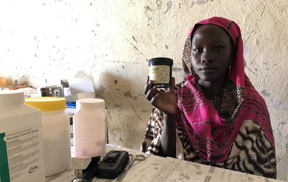 Mukuma Hamad, a volunteer health worker, holds a container of folic acid, the only assistance she can give pregnant women who visit the lone health clinic in Hadara village, in rebel-controlled Southern Kordofan. 