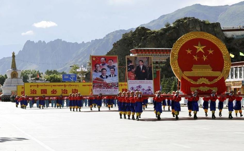 表演队伍扛著巨大的中国国徽和政府领导人照片，参加庆祝西藏自治区成立50周年大会，拉萨。