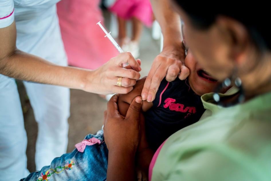 Trabajadora sanitaria que colabora con la Organización Panamericana de la Salud vacuna a una niña venezolana en un puesto de vacunación en la frontera entre Colombia y Venezuela. 27 de julio de 2018.