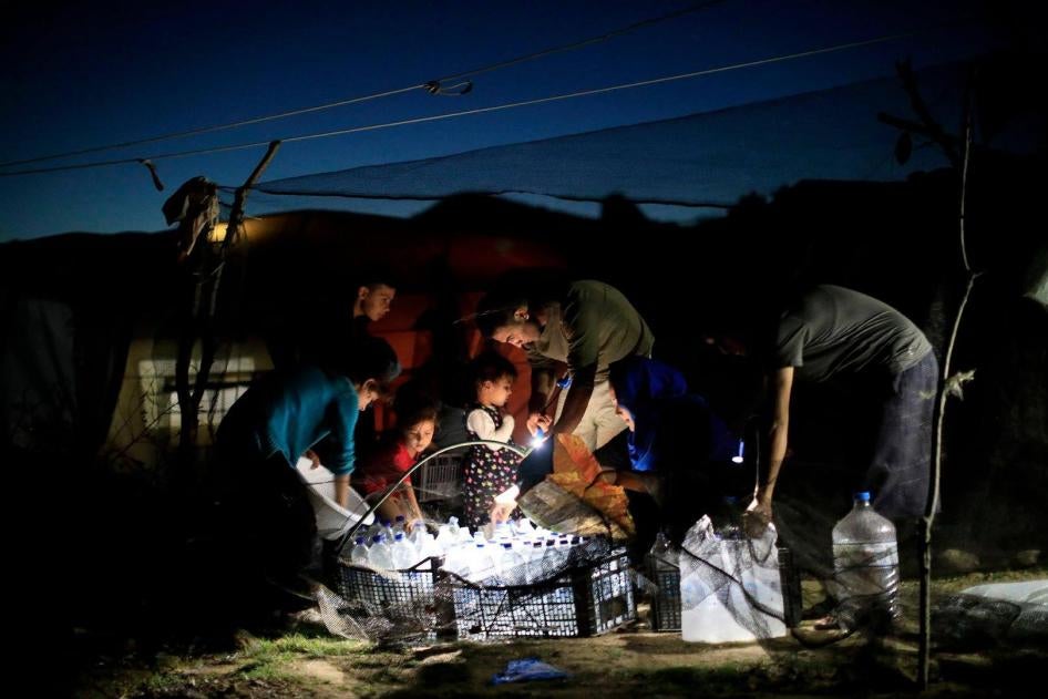 Asylum seekers outside their tent in the "Olive Grove", a makeshift camp outside Moria camp on the island of Lesbos on October 31, 2018.