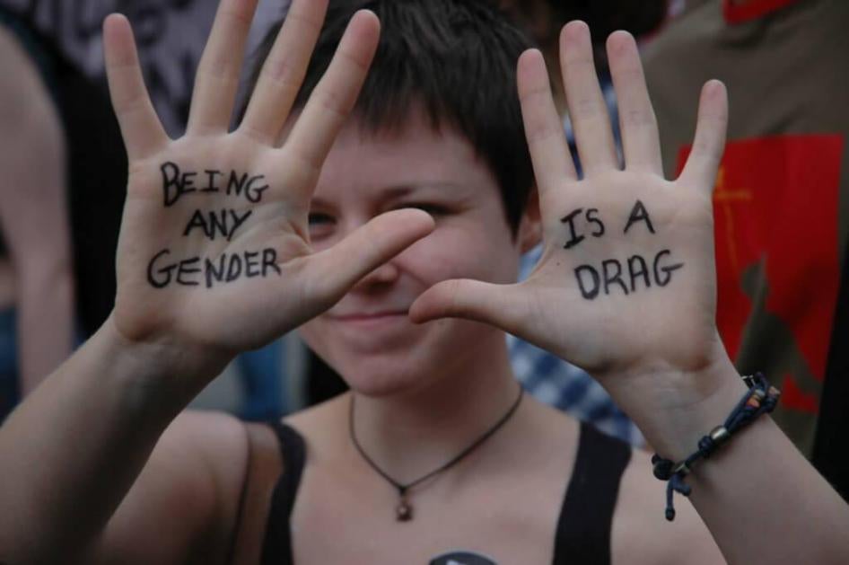 A woman taking part in London Pride, 2012, holds up her hands to show the words "being any gender is a drag".
