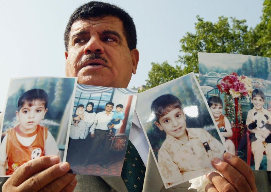 داود موسى، والد بهاء موسى الذي توفي في 2003 في عمر 26 عاما رهن الاحتجاز من قبل جنود بريطانيين في العراق، رافعا صور ابنه وصورة عائلية أمام وسائل الإعلام، بعدما وصوله إلى جلسة بمحكمة بريطانية في 28 يوليو/تموز 2004 حول انتهاكات حقوق الإنسان في العراق. © 2004