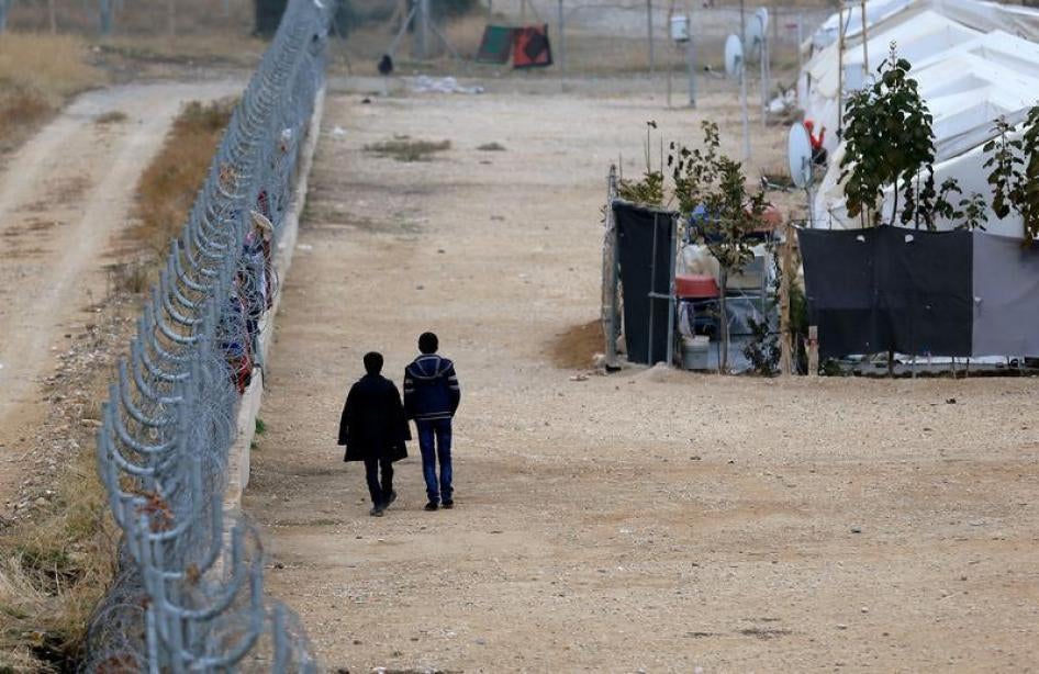 Deux Syriens marchent le long d'une clôture près de la frontière turco-syrienne dans la province de Gaziantep, en Turquie, le 30 novembre 2016.