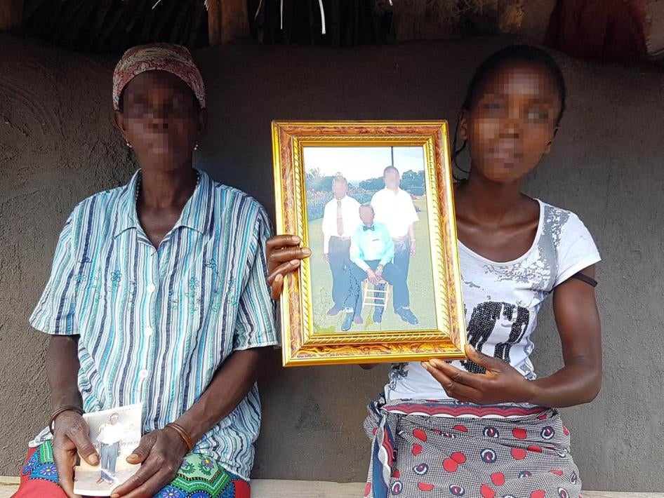 A esposa e a filha do regulo (chefe tradicional) de Muxungue, Makotori José Mafussi, mostram uma foto de Mafussi (sentado) e de dois familiares. Homens que se crê serem combatentes da Renamo mataram Mafussi em sua casa em 21 de julho de 2016. 