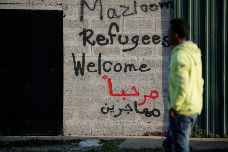 : Seorang migran melintas di depan tulisan "Pengungsi Diterima" pada sebuah tembok dekat bekas "Hutan" di Calais, Prancis, 23 Agustus 2017. 