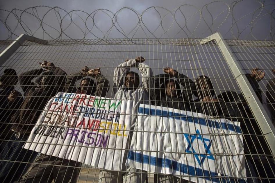 مهاجرون أفارقة يلوحون من خلف سياج خلال احتجاج على سياسة الاحتجاز التي تمارسها إسرائيل تجاههم، في حولوت، المركز الإسرائيلي للاحتجاز في صحراء النقب، جنوب إسرائيل، 17 فبراير/شباط 2014.©  2014 رويترز 
