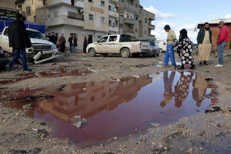 أشخاص يمشون بجانب بركة ماء اختلطت فيها الدماء في موقع تفجير سيارتين مفخختين بالقرب من مسجد في منطقة السلماني في بنغازي، أسفرت عن عدد كبير من القتلى والجرحى، ليبيا، 24 يناير/كانون الثاني 2018. © 2018 رويترز