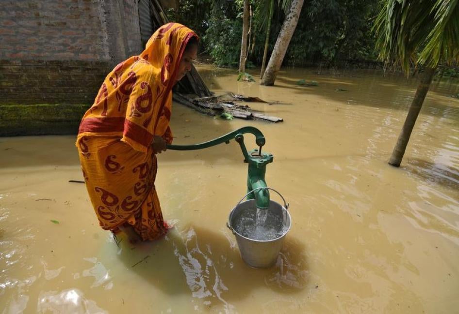 Une femme indienne récolte de l'eau dans un seau en se servant d’une pompe à eau manuelle dans un village du district de Sonitpur touché par des inondations dans l'État d'Assam, dans le nord-est de l’Inde, le 11 septembre 2017.