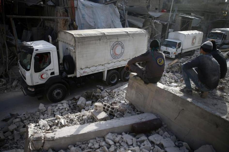 Civil defence members sit amid the rubble as they watch an aid convoy of Syrian Arab Red Crescent driving through the besieged town of Douma, Eastern Ghouta, Damascus, Syria March 5, 2018. 