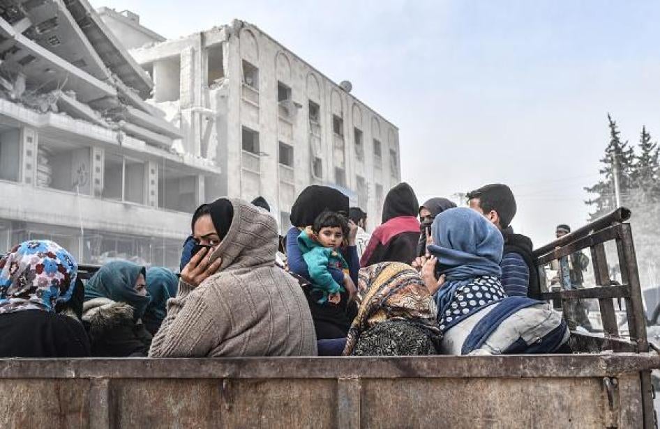 Şênîyin di paş barkêşekê de rûniştîne kû ew ji bajarê Efrînê bazdidin 18ê Adara 2018an, piştî ku hêzên tirkan û grûpên çekdar ên hevalbend bajarê bi piranî kurd in kontrol kir. © Bulent Kilic/AFP/Getty Images