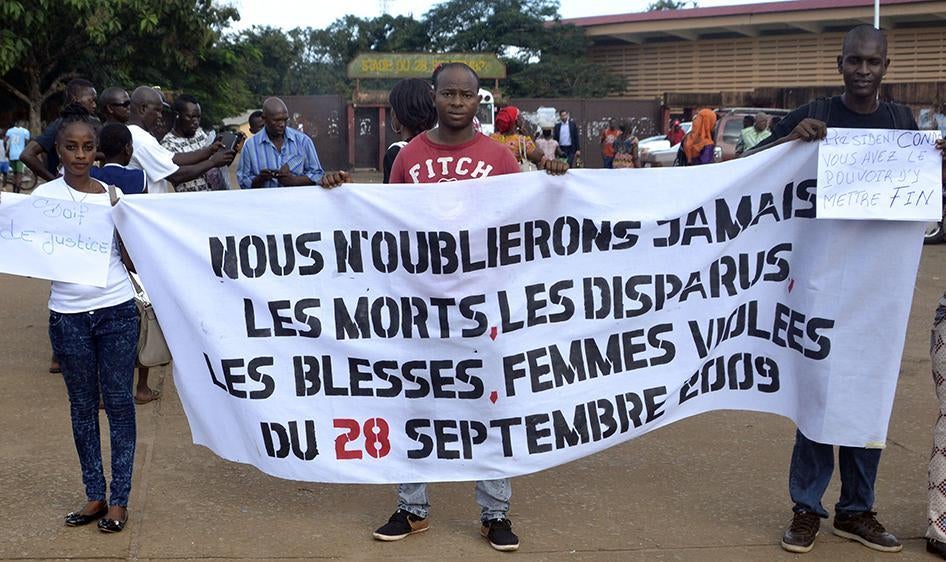 Des personnes déploient une bannière le 28 septembre 2016, dans la capitale de la Guinée, Conakry, en souvenir des morts, des disparus, des blessés et des femmes violées le 28 septembre 2009.
