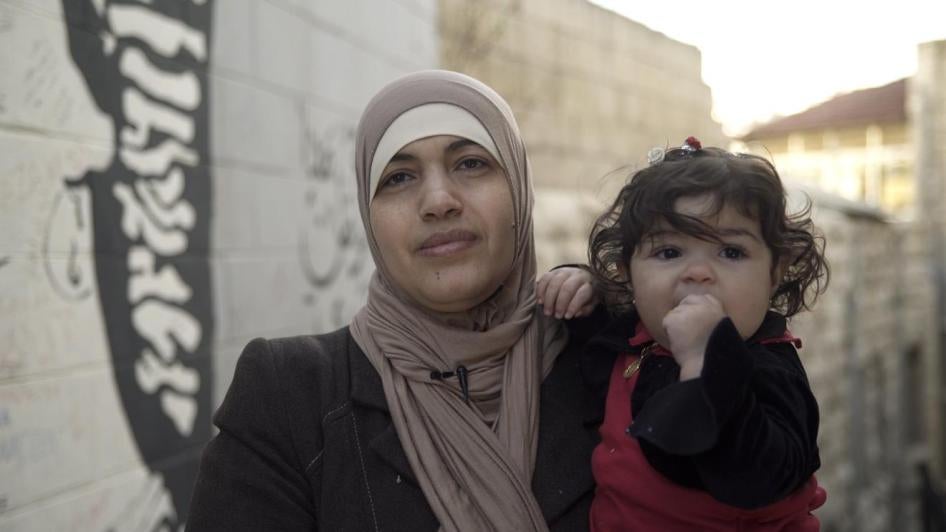 امرأة أردنية متزوجة من رجل أجنبي، تحمل طفلتها، وهي واحدة من أبنائها الأربعة غير الحاصلين على الجنسية الأردنية. الصورة في 9 فبراير/شباط 2018 في عمان، الأردن. 