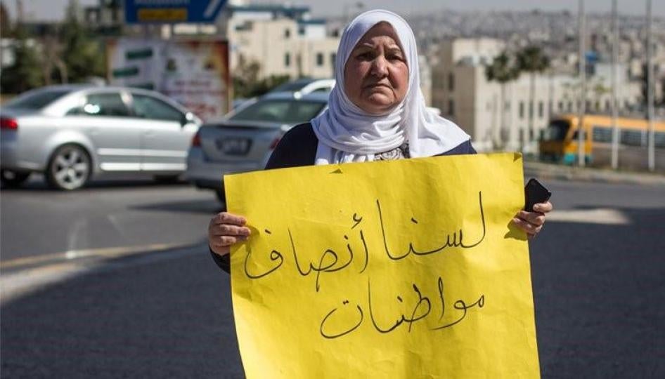 The late Nima Habashneh, a leading activist in the movement for equal citizenship rights in Jordan, holds a sign that reads, “we are not half citizens”, during a protest in front of the Prime Ministry in Amman, Jordan on March 22, 2014.