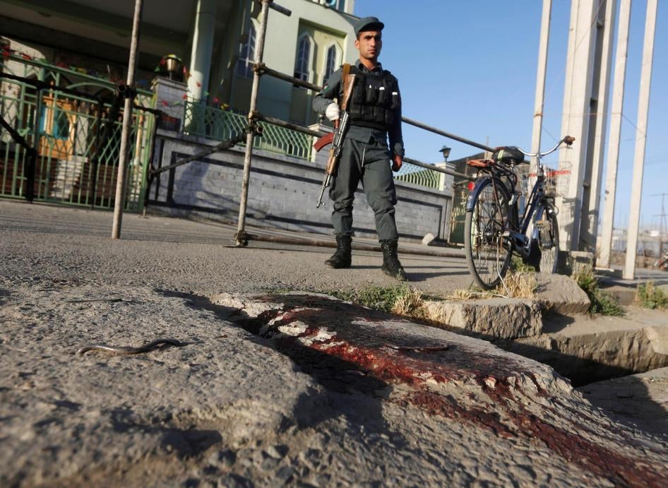 A policeman stands on a bloodstained street following the suicide attack at the Al-Zahra Mosque in Kabul, June 16, 2017.