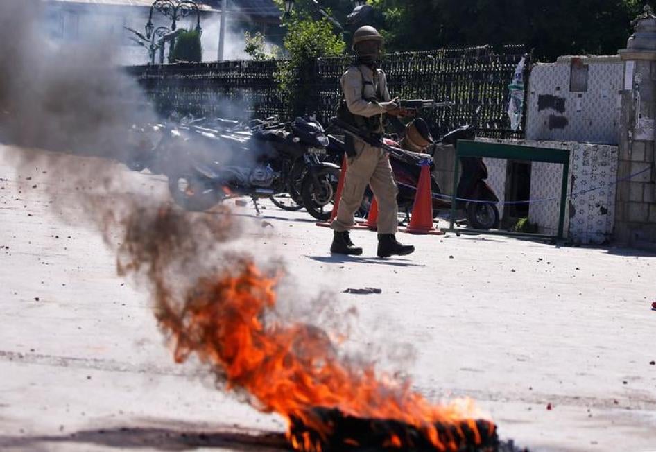 An Indian police officer walks past a burning tire during a protest after Friday prayers in Srinagar, May 25, 2018. REUTERS/Danish Ismail