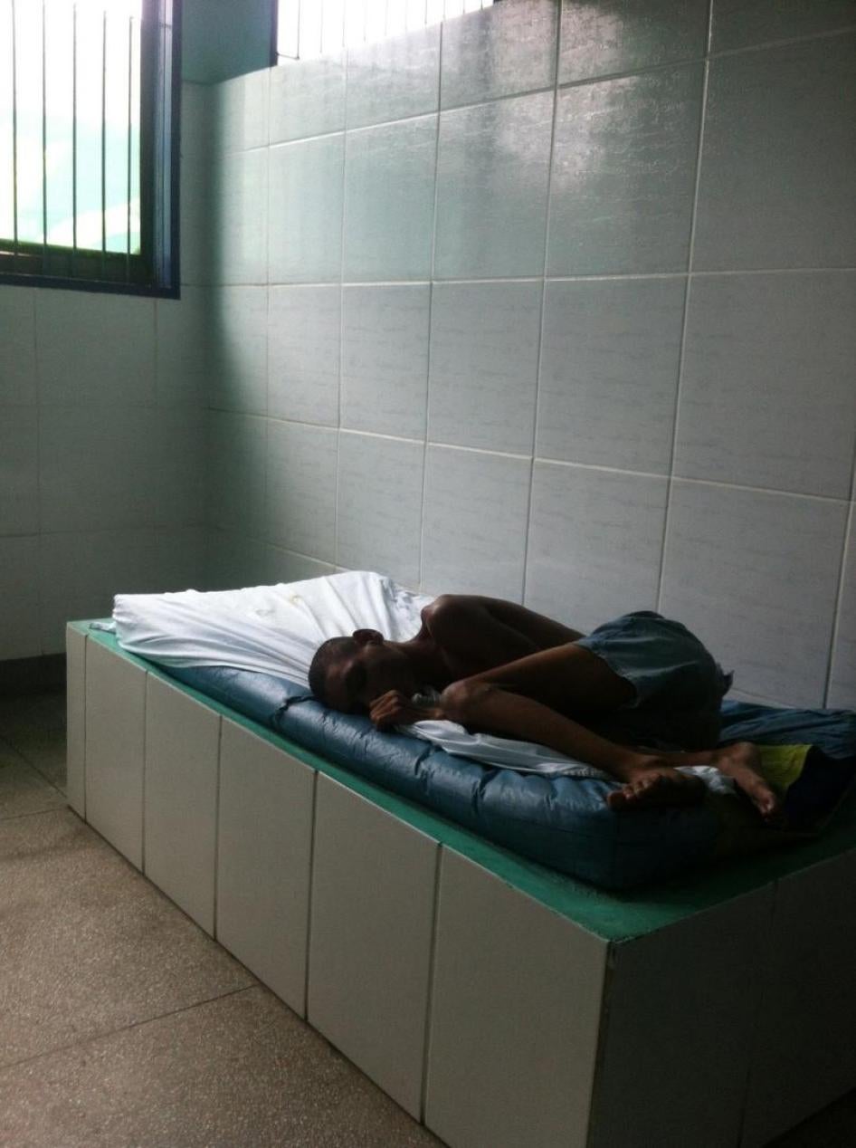 Um rapaz deitado em um colchão em um quarto vazio em uma instituição no Rio de Janeiro. A maioria dos adultos e crianças com deficiência em instituições tem poucos ou mesmo nenhum item pessoal. 