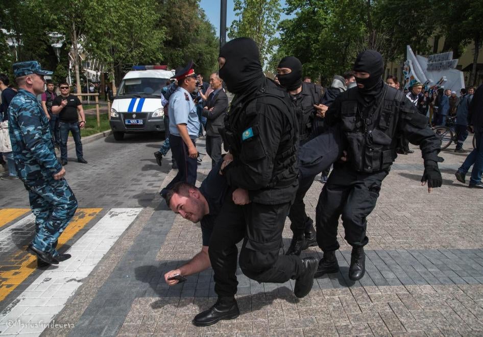 Masked law enforcement officers detain protester at a May 10 rally in Almaty, Kazakhstan.
