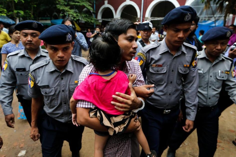 Kyaw Soe Oo carries his daughter while escorted by police outside a court in Yangon, Myanmar, June 18, 2018.