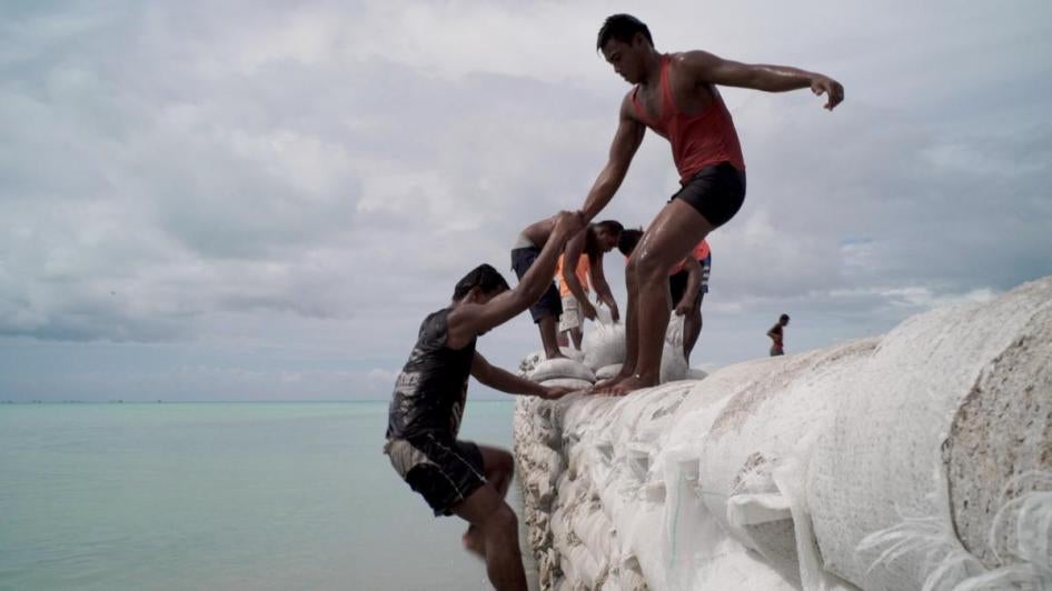 Men construct a seawall in Kiribati, located in the Pacific Ocean. Kiribati’s islands may become uninhabitable as ocean levels rise due to climate change. 