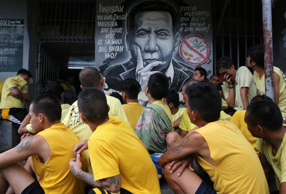 Detainees sit next to an anti-drug mural of Philippines President Rodrigo Duterte inside the Manila City Jail, October 16, 2017.