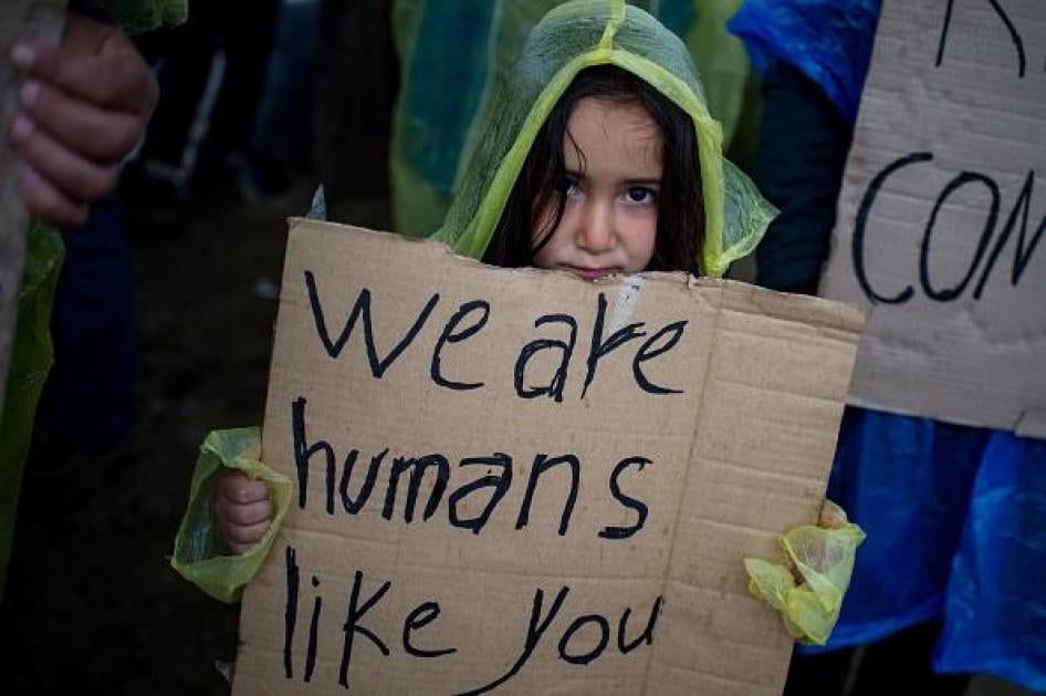 Una bambina tiene in mano un cartello durante una protesta di migranti e rifugiati vicino al paese di Idomeni, Grecia, per chiedere la riapertura della frontiera con Macedonia, 23 marzo 2016.