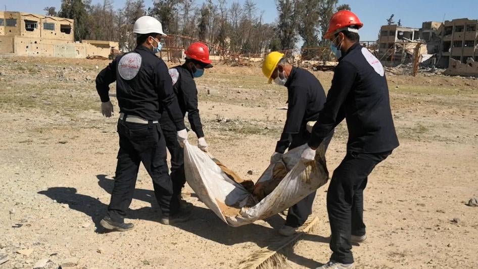 Members of the First Responders Team in Raqqa city, Syria exhume a body from a mass grave at the al-Rashid playing field.
