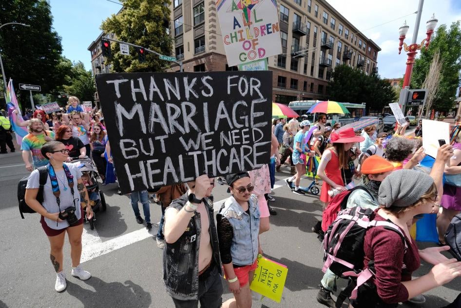 Participants at the Trans Pride March on June 16, 2018 in Portland, OR, display a placard calling for stronger healthcare protections. 