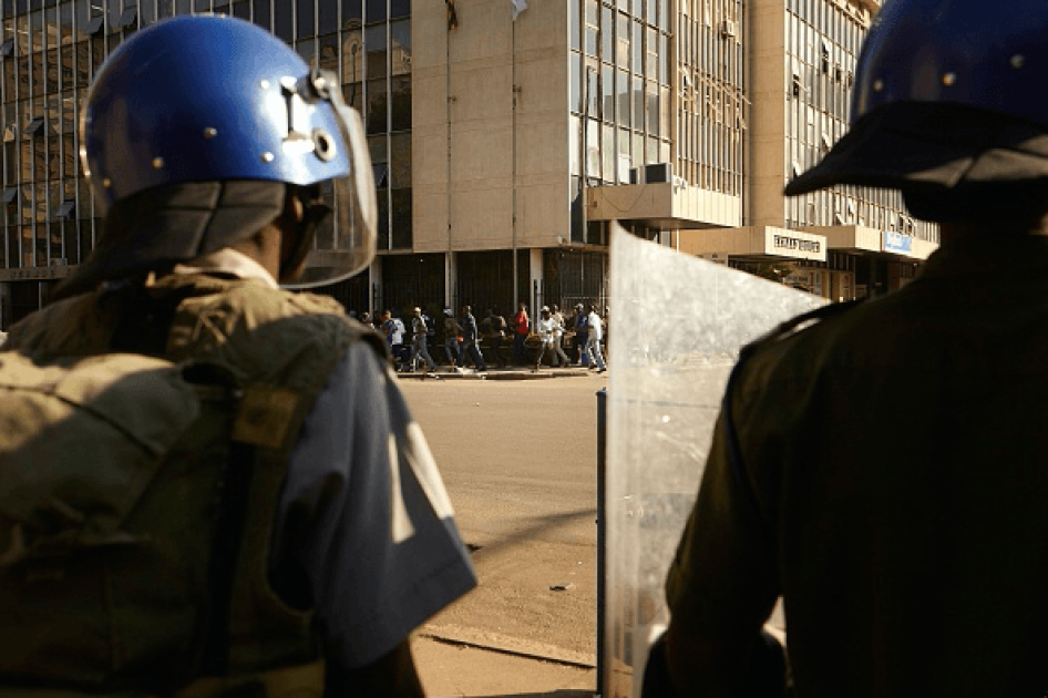 Zimbabween soldiers stand guard as citizens run through the Harare's streets, on August 1, 2018. 