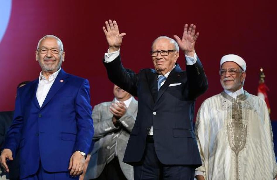 الرئيس التونسي الباجي قائد السبسي وزعيم حزب النهضة الإسلامي راشد الغنوشي ونائب رئيس حزب النهضة عبد الفتاح مورو يلوّحون إلى الجمهور في 20 مايو/أيار 2016 خلال افتتاح مؤتمر النهضة الذي يستمر 3 أيام في العاصمة تونس. 