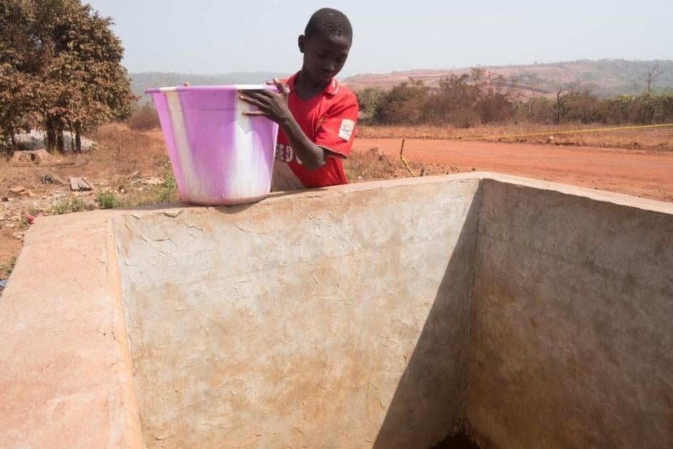 Un garçon puise de l’eau dans une citerne du village de Lansanayah, dans la région de Boké, remplie par les camions-citernes de la Société Minière de Boké (SMB). D’après les villageois, l’arrivée de la SMB a endommagé les sources d’eau naturelles locales,