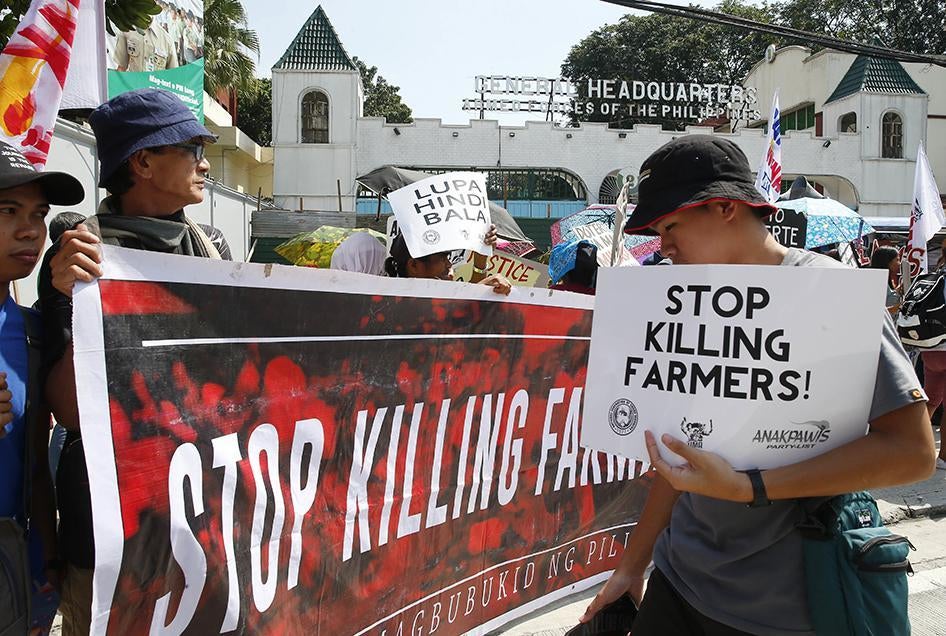 Protesters display placards during a rally outside a police and a military camp to protest the weekend killings of nine farmers in Sagay city