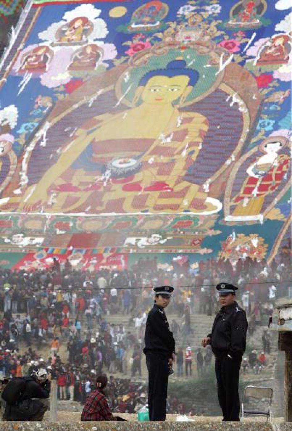 巨型释迦牟尼唐卡于西藏拉萨近郊展出，数名警员从哲蚌寺屋顶监视前来礼佛的群众。