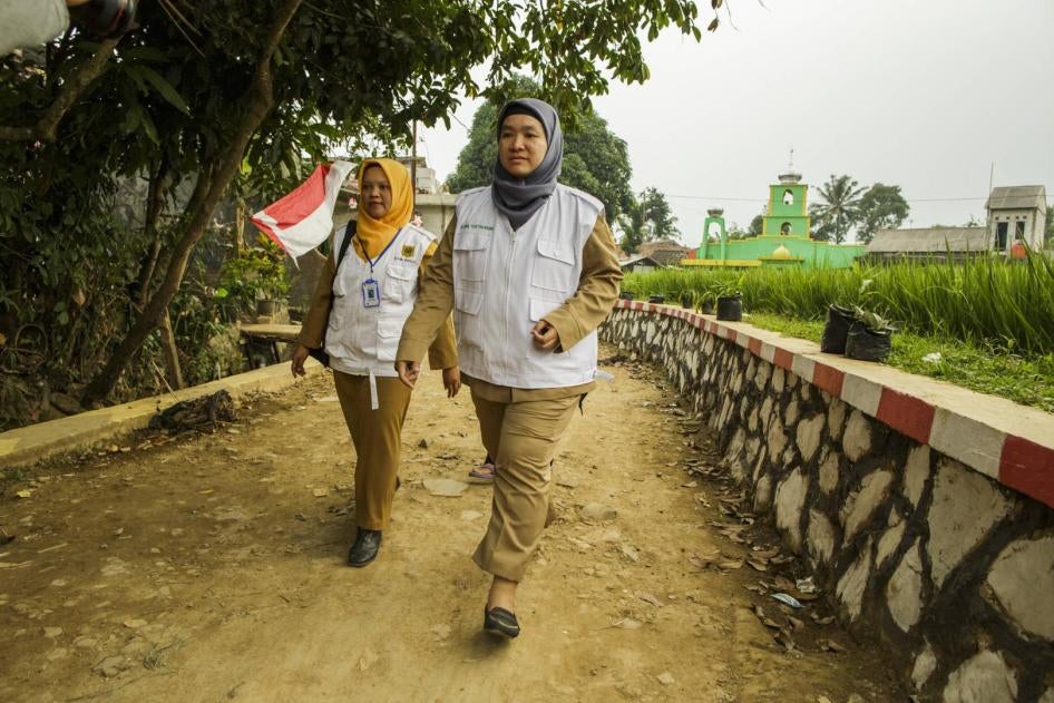 Two community health workers walking in a village in Indonesia.
