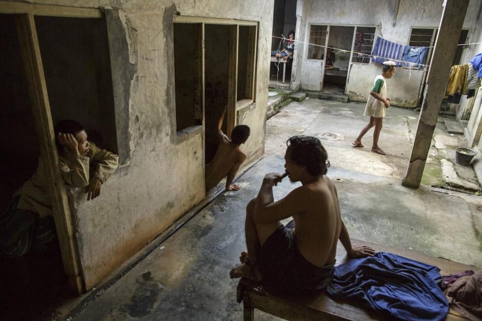 Men sitting and standing in an institution in unsanitary conditions