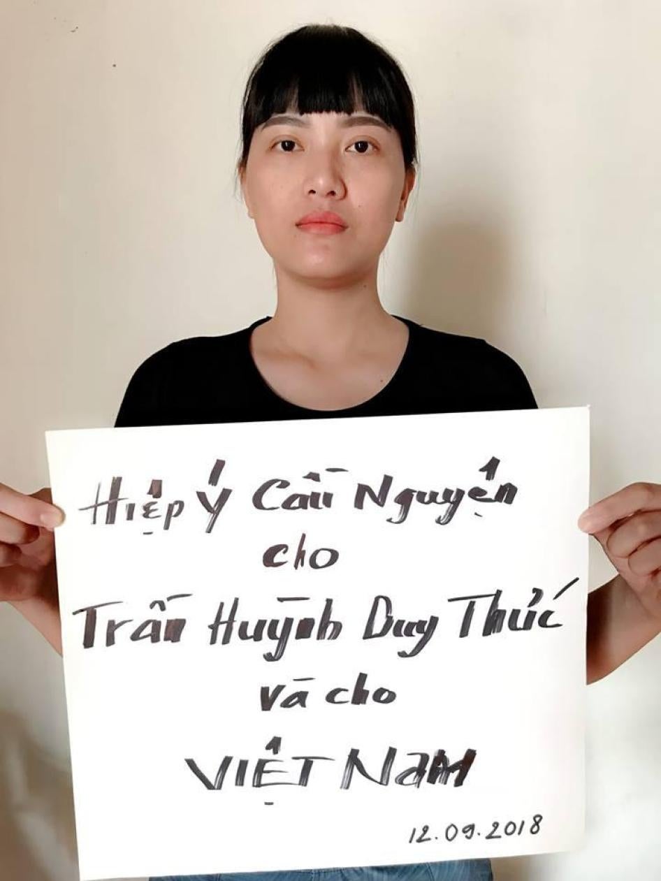 Huynh Thuc Vy holds a sign that reads "Praying for Tran Huynh Duy Thuc and for Vietnam. Sept 12, 2018".