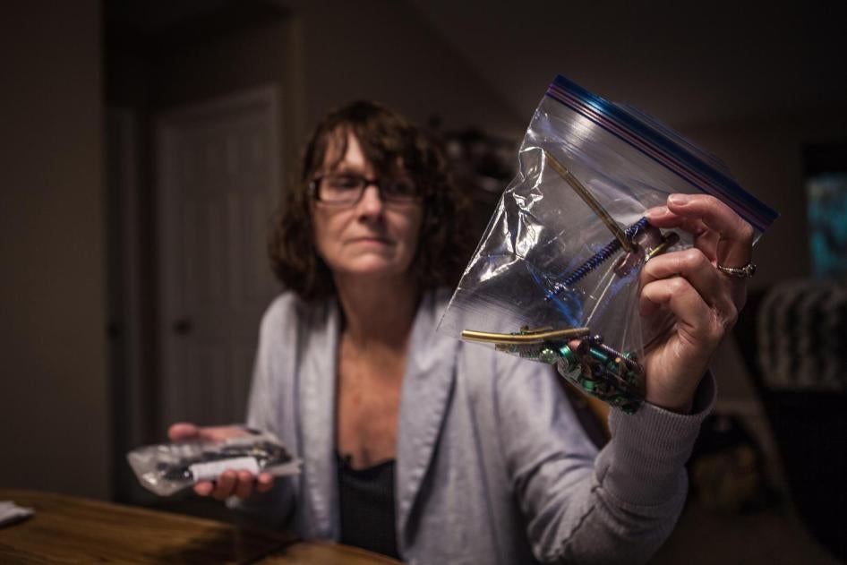 Maria Higginbotham, 57, holding screws and bolts removed from her back in a recent surgery.