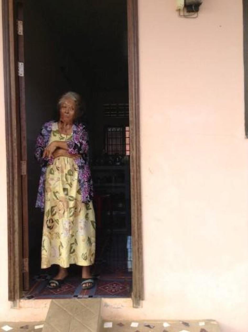 Madame Thong Kham stands in the doorway of her home on October 31, 2014.