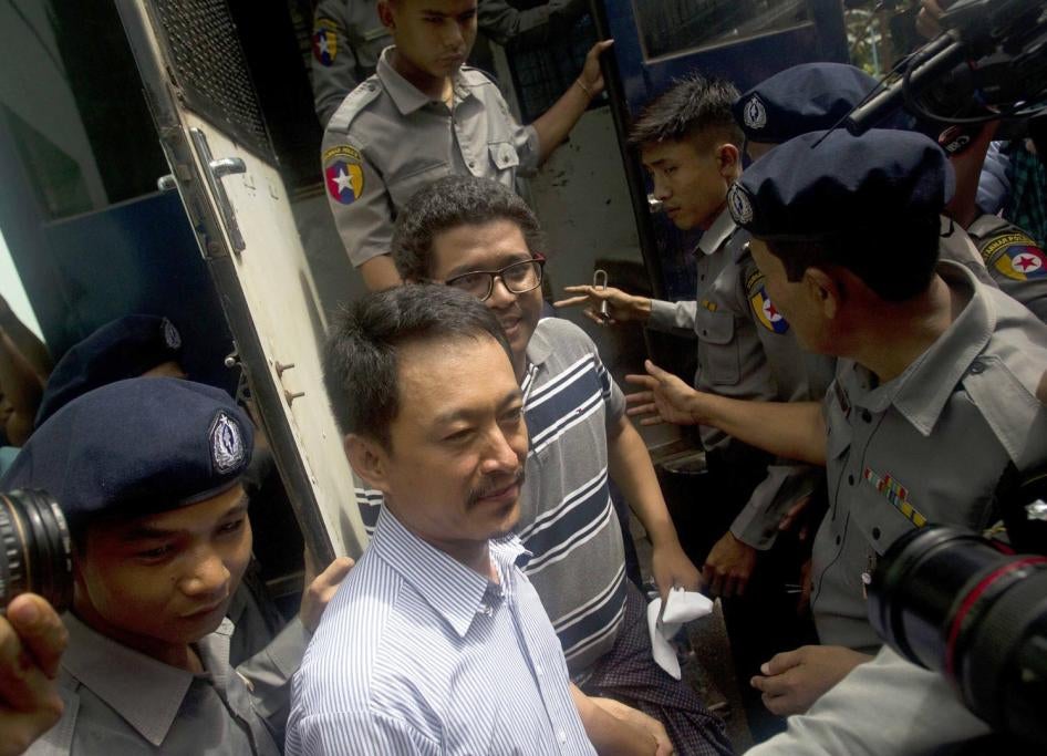 Kyaw Min Swe (center left) and columnist British Ko Ko Maung are escorted by police after arriving at the township court in Yangon, June 16, 2017. 