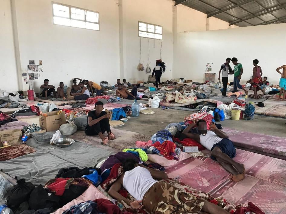 رجال في إحدى غرف مستودع واسع في مركز احتجاز عين زارة، طرابلس، 5 يوليو/تموز 2018. 